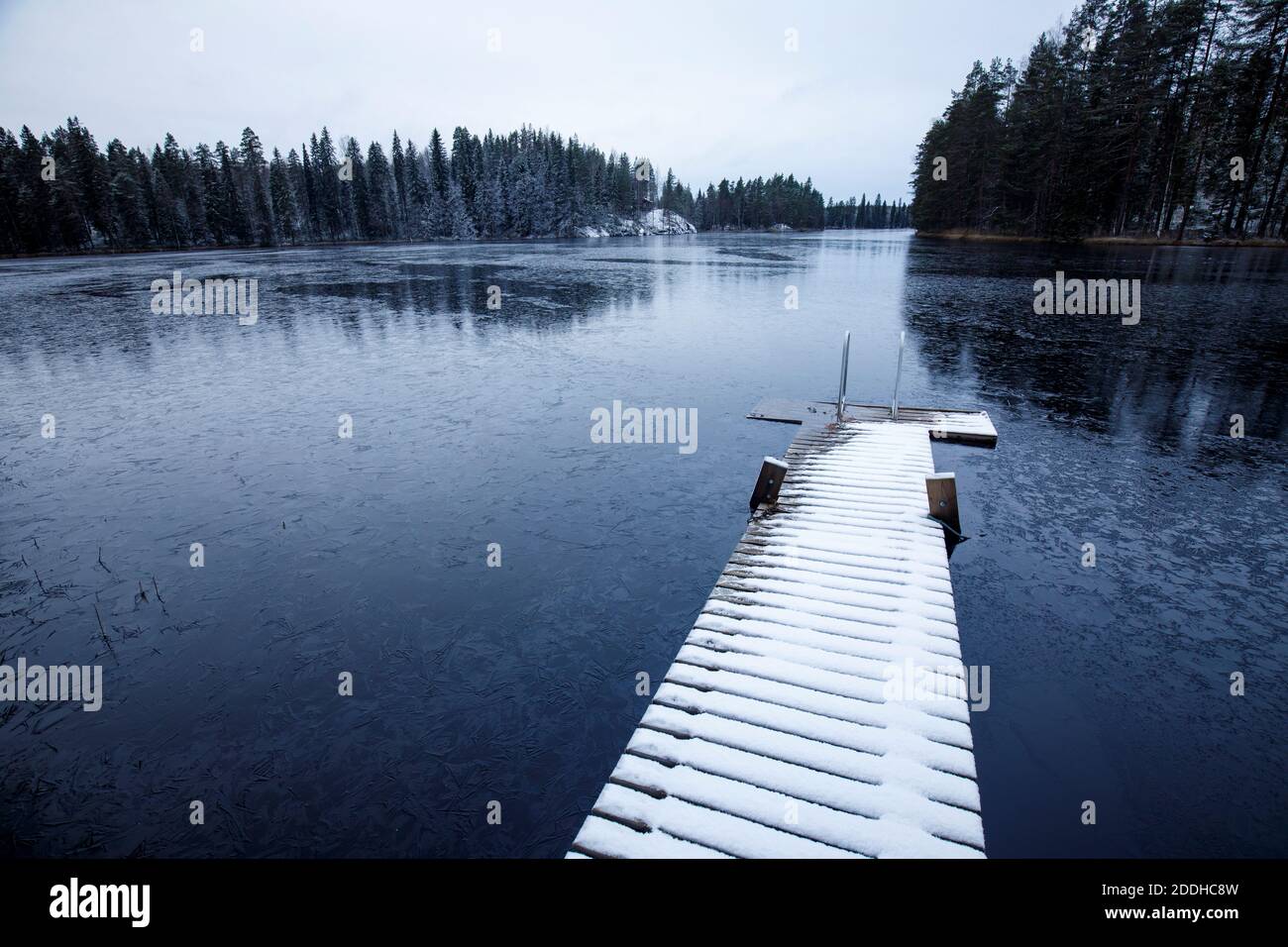 Innevato molo di legno coperto e sci di ghiaccio lago di foresta a Winter , Finlandia Foto Stock