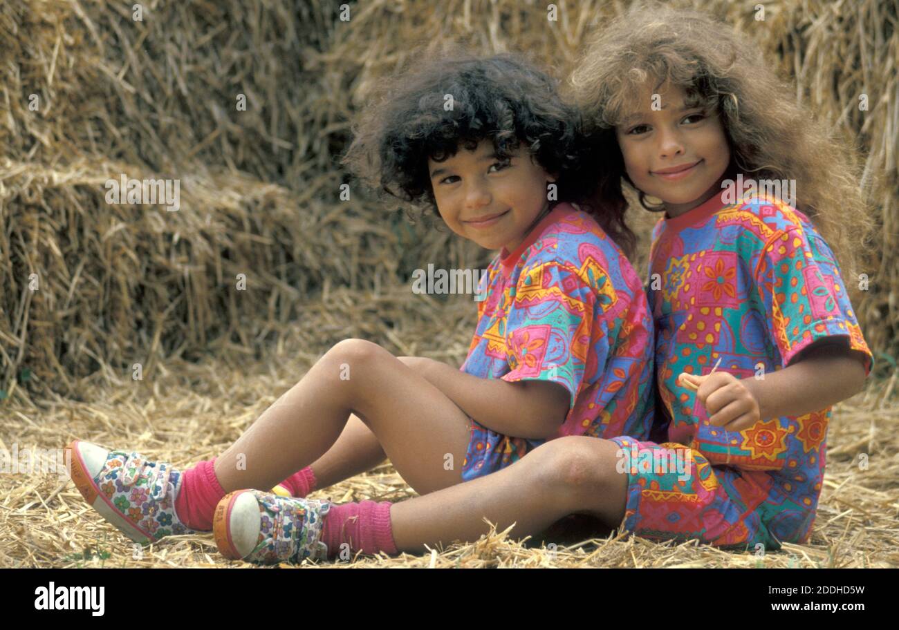 due piccole sorelle che si siedono sulla balla di fieno Foto Stock
