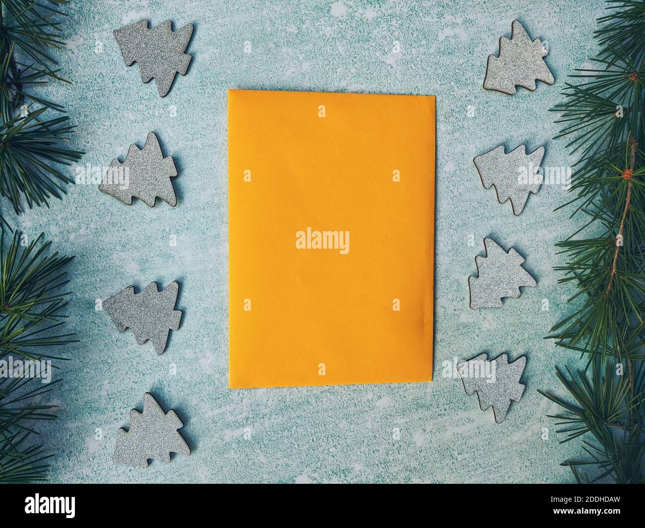 Composizione di Natale o Capodanno. Busta gialla di carta con rami di abete rosso, decorazioni su sfondo blu. Stile di posa piatto. Saluto di Capodanno c Foto Stock