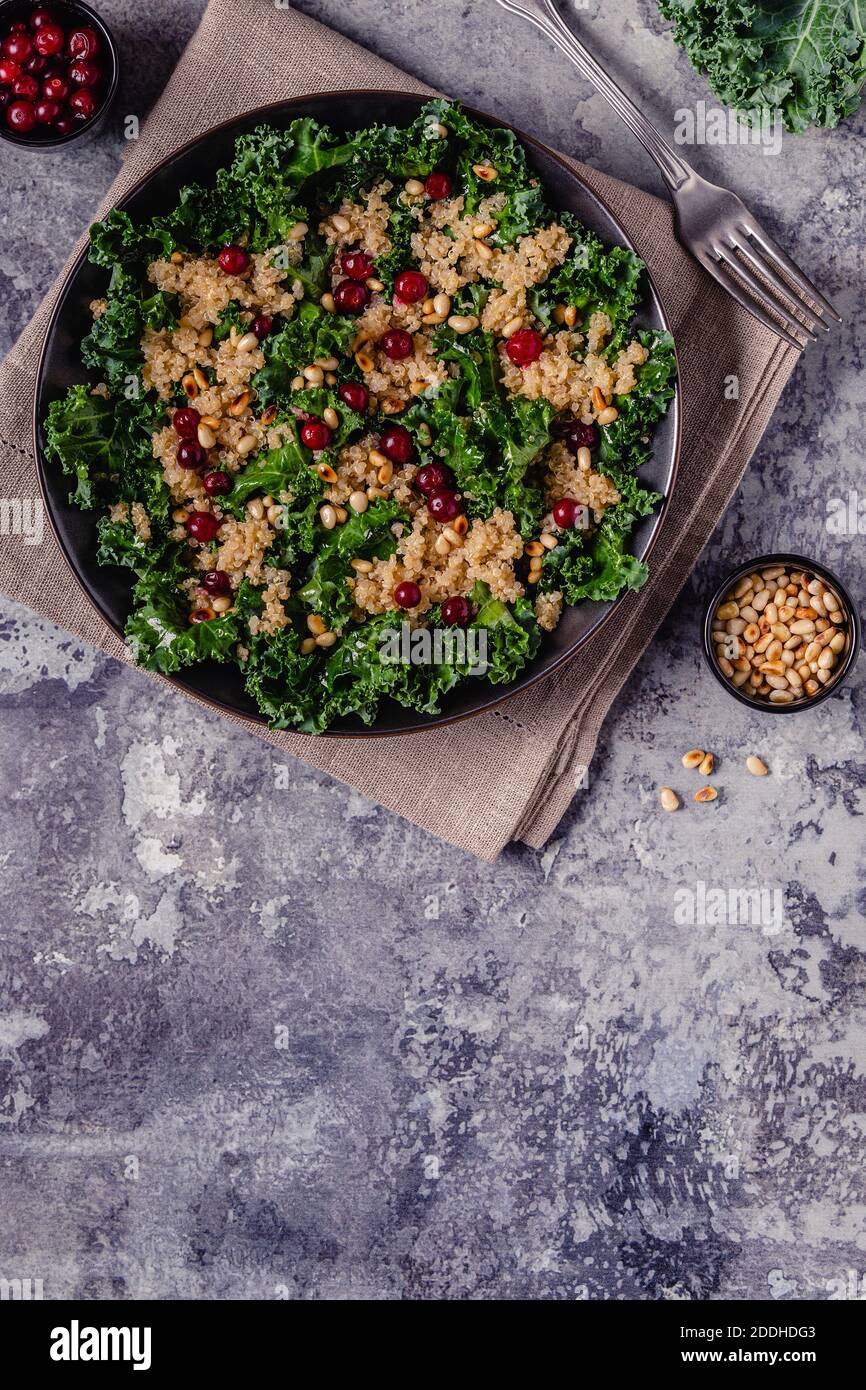 Insalata sana di kale crudo e quinoa con mirtillo rosso e pinoli. Vista dall'alto. Foto Stock