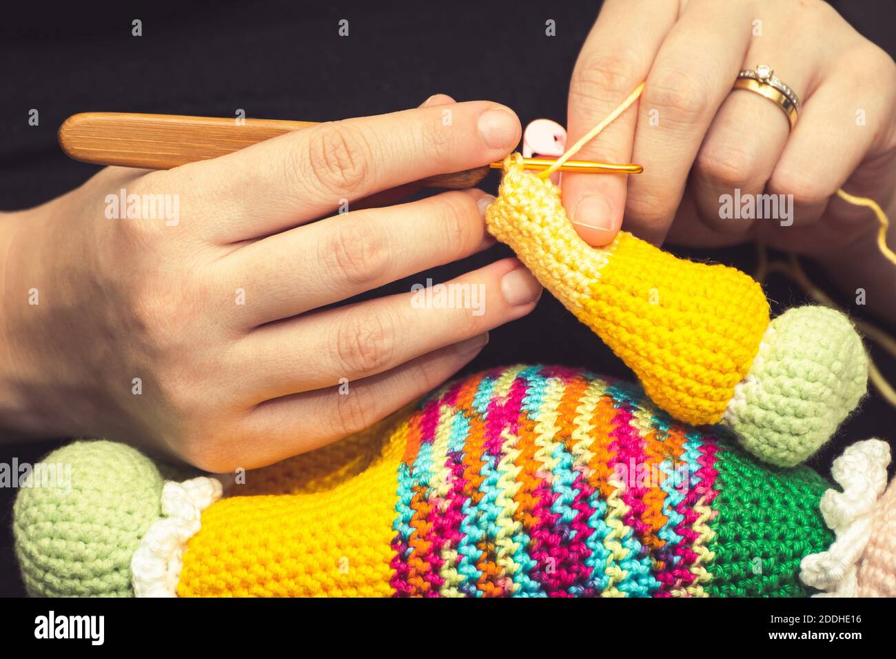 Primo piano sulla mano di una donna che usa un ago da maglieria per cucire  una bambola a uncinetto con un filo di lana Foto stock - Alamy
