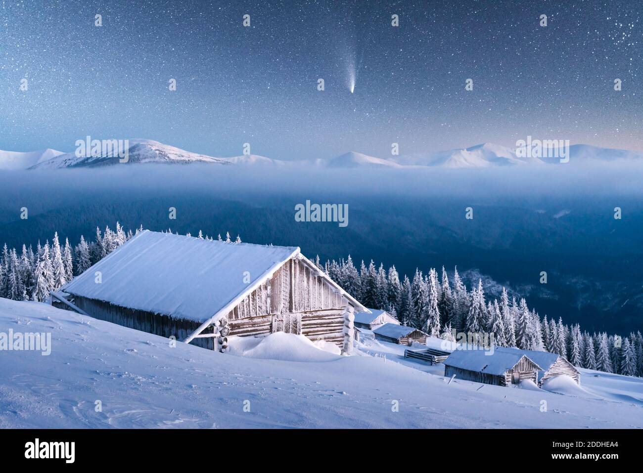 Fantastico paesaggio invernale con casa in legno in montagne innevate. Cielo stellato con cometa e capanna innevata. Vacanza di Natale e concetto di vacanza invernale Foto Stock
