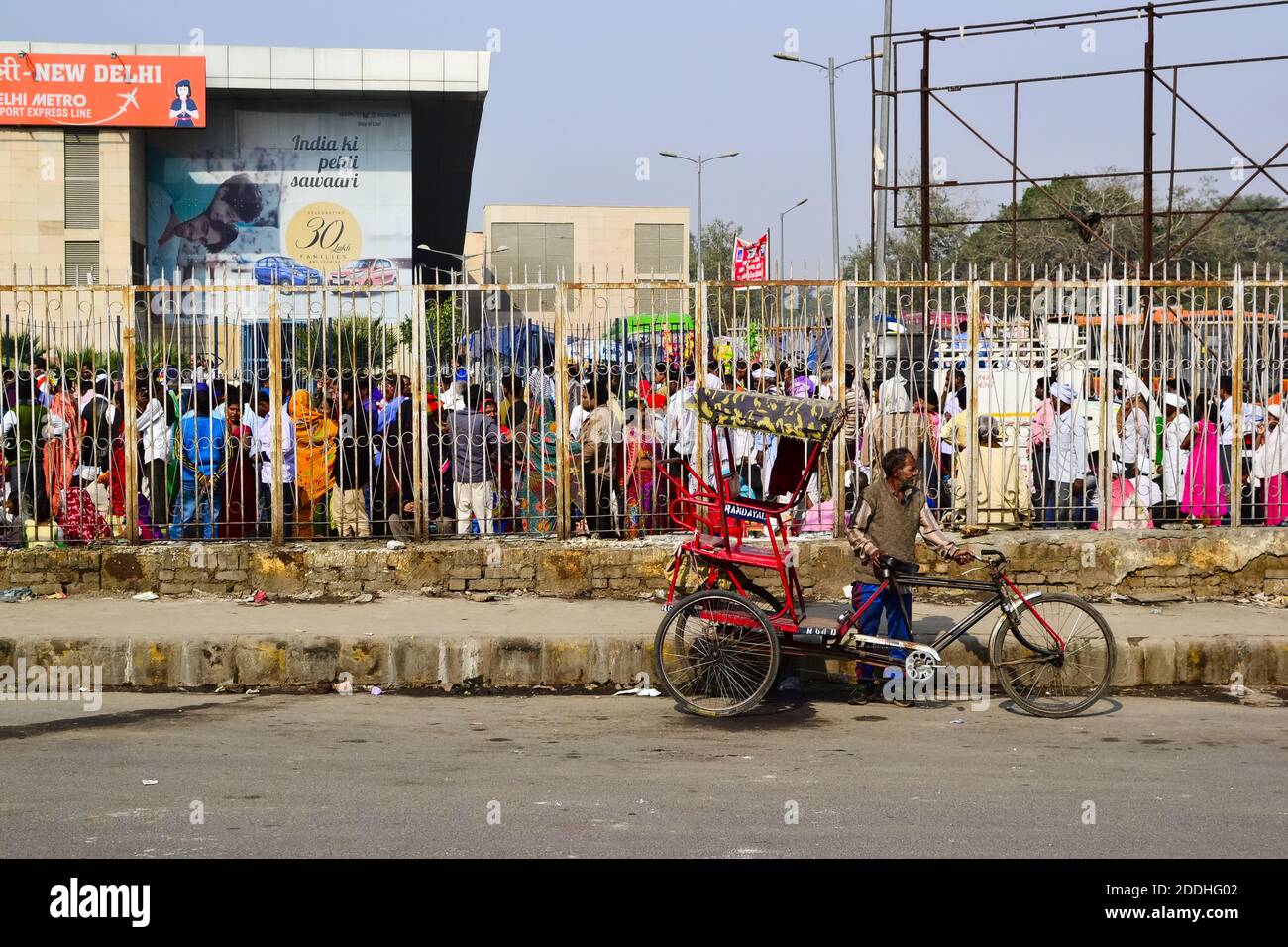 New Delhi, India - Novembre, 2016: Rickshaw vecchio uomo in attesa di clienti vicino alla bicicletta sulla stazione ferroviaria di New Delhi. Folla di persone in fila Foto Stock