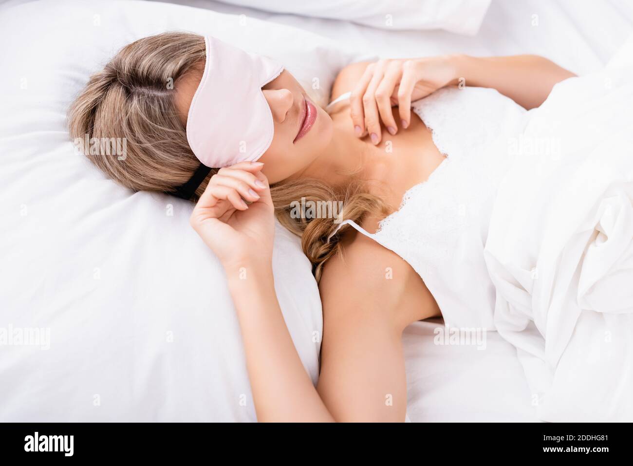 Giovane donna in bendle sdraiata su biancheria da letto bianca al mattino Foto Stock