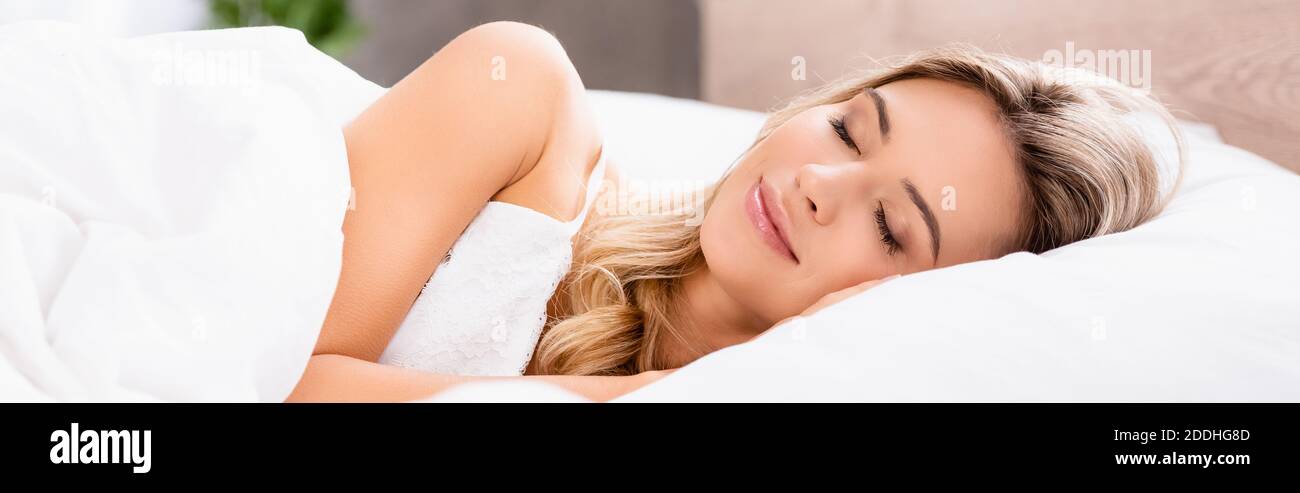 Giovane donna che dorme su biancheria da letto bianca al mattino, striscione Foto Stock