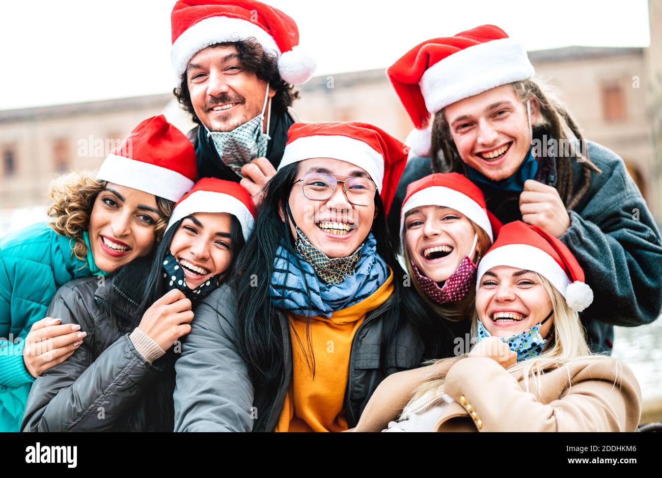 Persone multirazziali che prendono selfie indossando maschera facciale e cappello di santa - nuovo concetto di festa di Natale normale con amici felici sorridenti insieme all'esterno Foto Stock