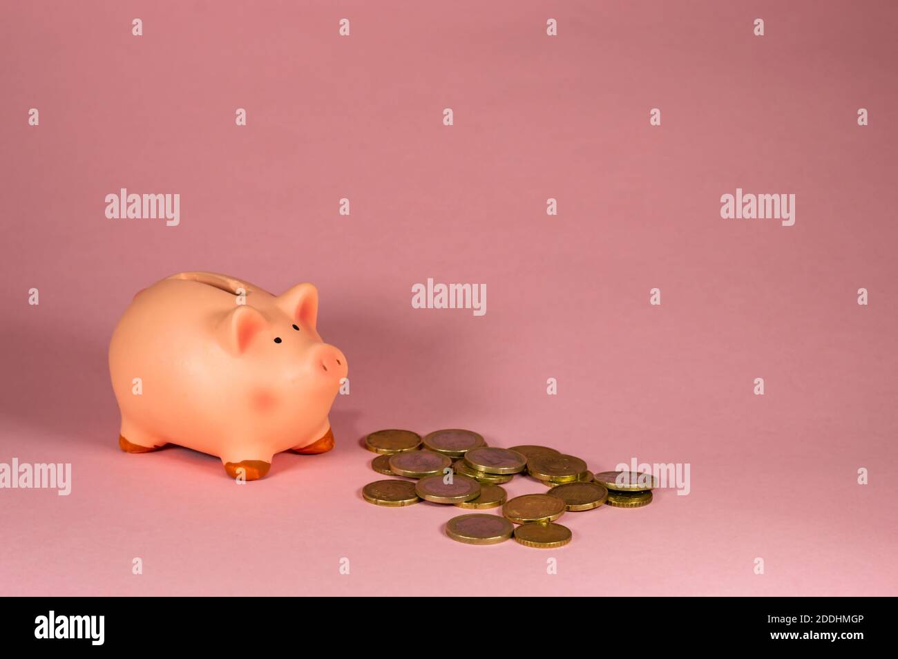 Primo piano di Piggy Bank con monete contro sfondo rosa Foto Stock