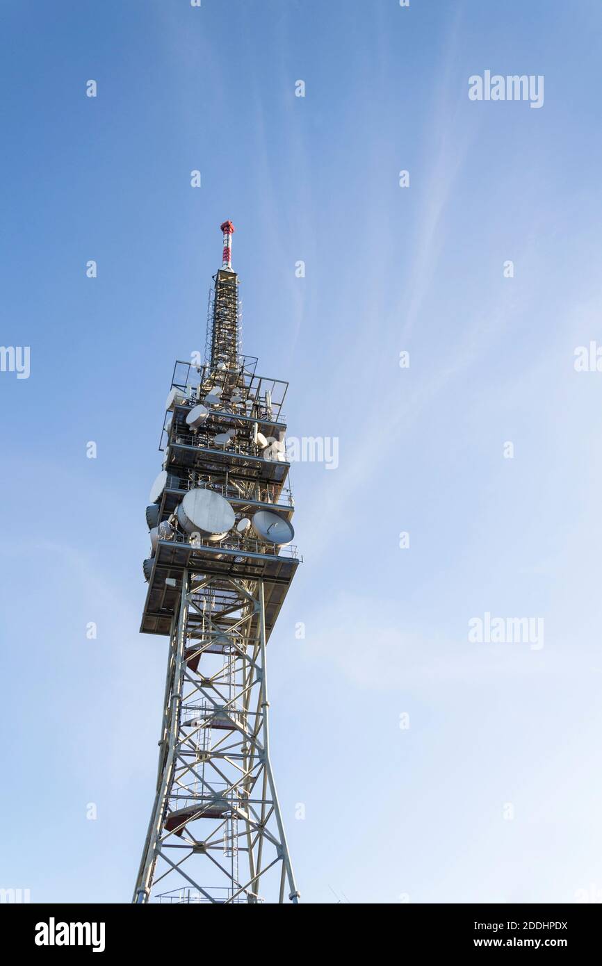 Torre per telecomunicazioni con trasmettitori e antenne, comunicazione wireless e concetto di reti cellulari a banda larga 5G, cielo blu chiaro sfondo wi Foto Stock