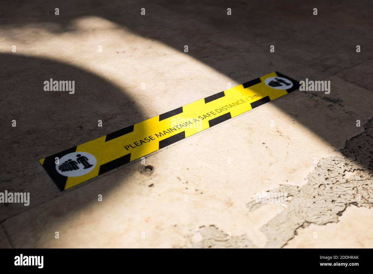 MANTENERE UN segnale DI DISTANZA DI SICUREZZA a terra, nero e giallo Banner sul pavimento, COVID-19 pandemia norme di sicurezza pubblica, distanza sociale Coronavirus Foto Stock