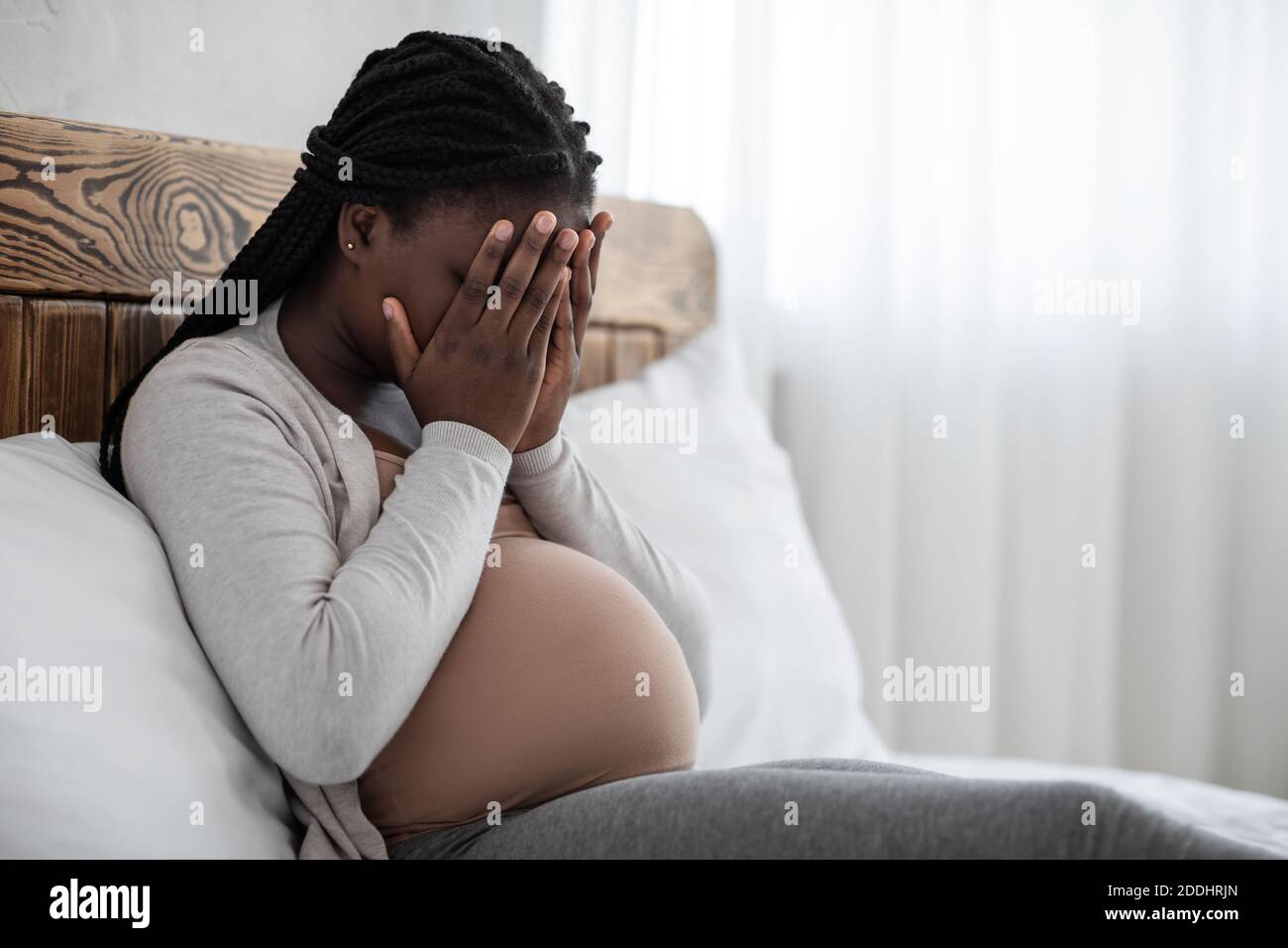 Cambiamenti emotivi durante la gravidanza. Donna incinta nera sconvolto coprendo il viso con le mani Foto Stock