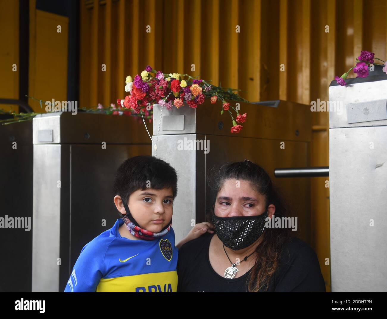 Buenos Aires, Argentina. 25 Nov 2020. Una donna e suo figlio, che indossa una maglia della squadra di calcio Boca Juniors, piangono Diego Maradona all'ingresso dello stadio la Bombonera, dove i fiori sono stati posati nell'area d'ingresso in onore della stella del calcio. Secondo i media, Maradona morì per un attacco di cuore nella sua casa a Tigre, a nord di Buenos Aires. Credit: Fernando Gens/dpa/Alamy Live News Foto Stock