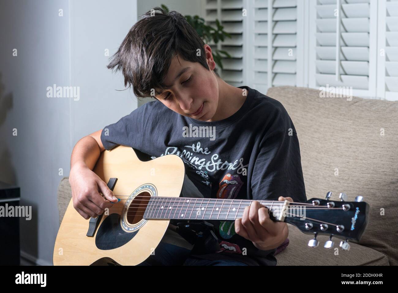 Teenager che suona la chitarra acustica a casa, Regno Unito Foto Stock