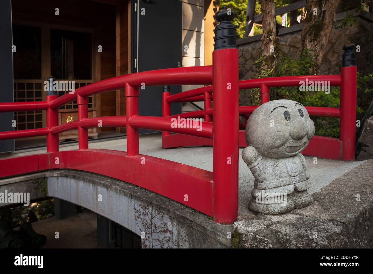 Vista verticale di un ponte rosso con il personaggio cartoon Anpanman nel tempio buddista di Daisho-in, Miyajima, Giappone Foto Stock