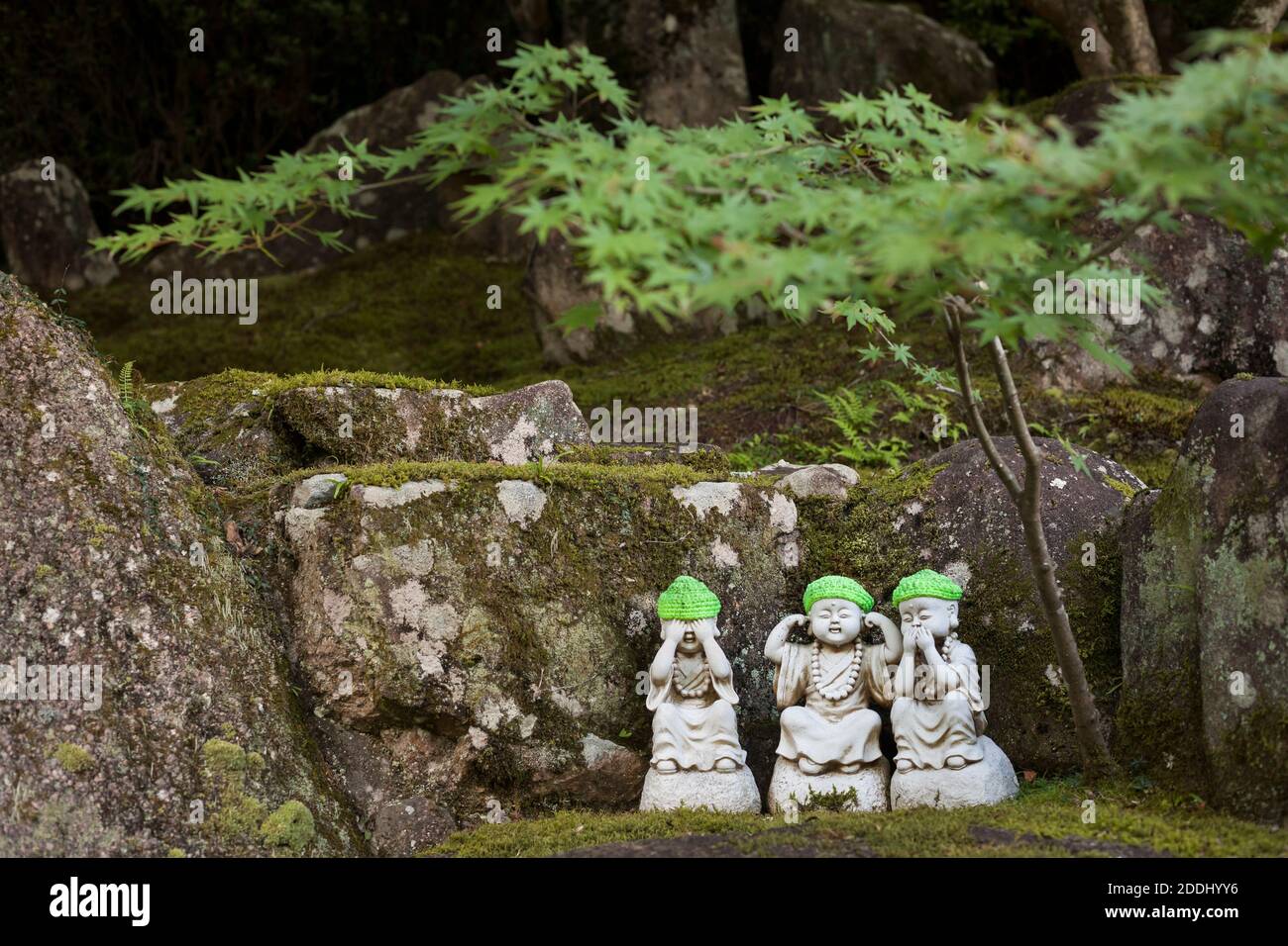 Foto orizzontale di tre statue Jizo in pietra di un piccolo acero nel tempio buddista di Daisho-in, Monte Misen, Miyajima, Isola di Itsukushima, Giappone Foto Stock