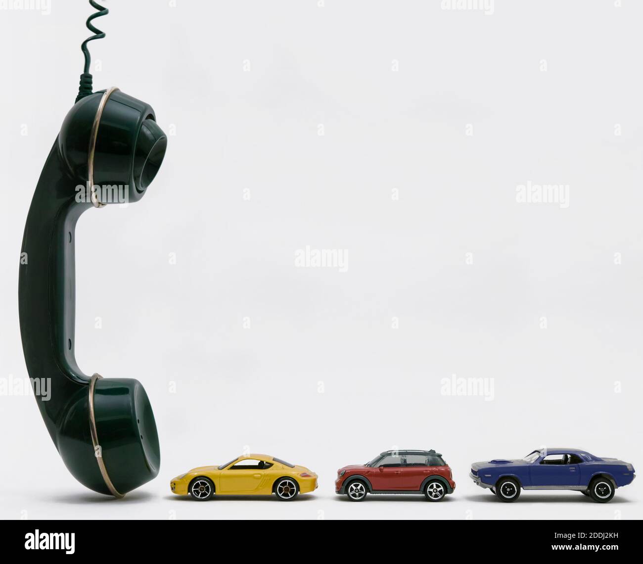 Tre piccole auto che aspettano di fronte a un telefono cellulare enorme, copia-spazio. Foto Stock