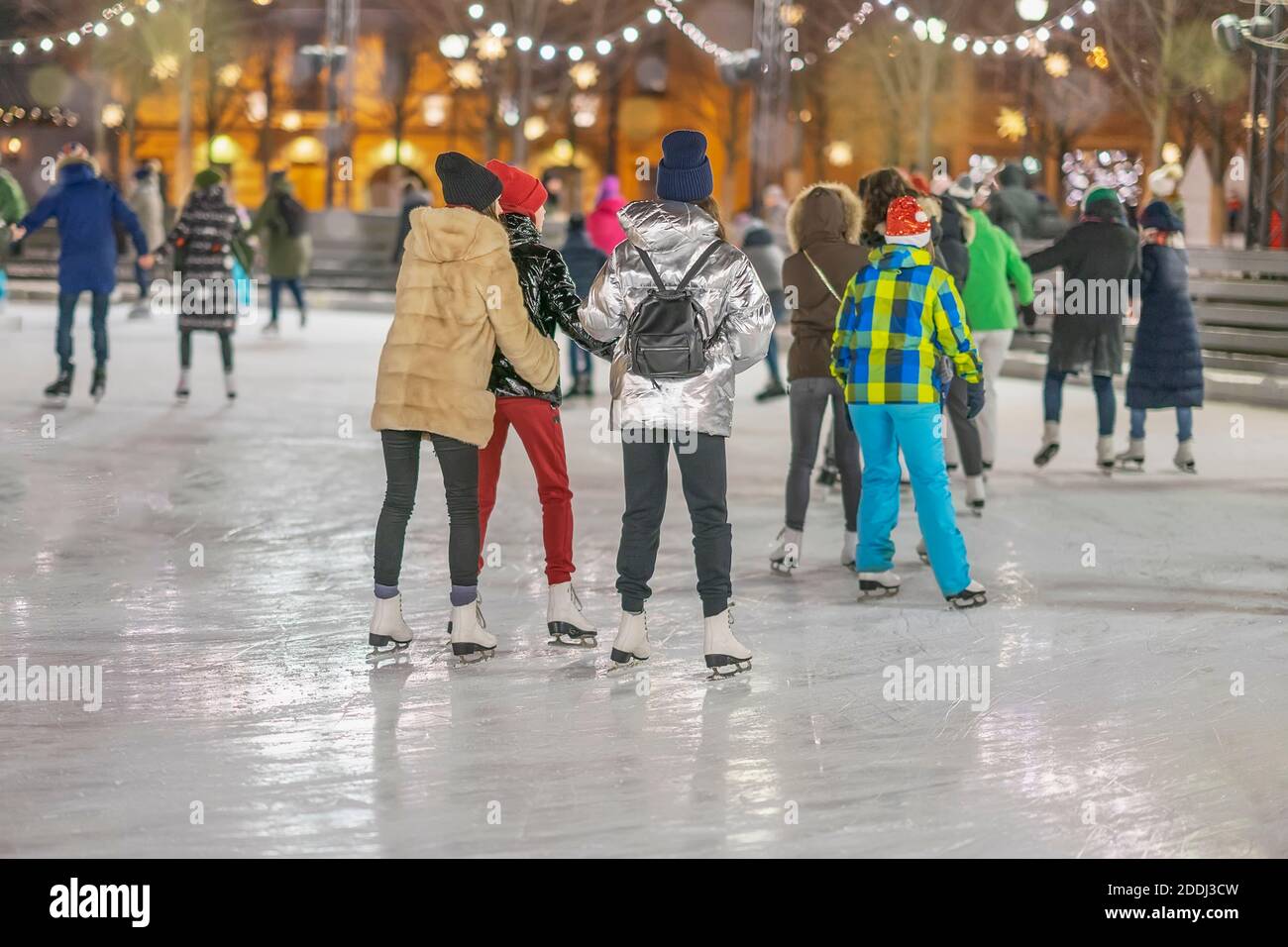 Happy Girlfriends pattinaggio su ghiaccio sulla pista di pattinaggio nel parco cittadino insieme. Sana attività invernale all'aperto Foto Stock