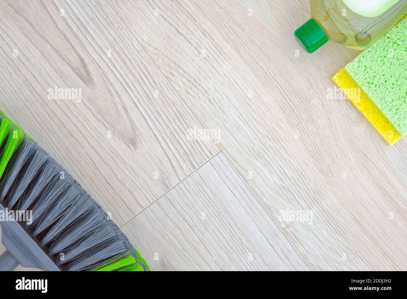 Set di prodotti per la pulizia verdi su sfondo di legno. Detergente in flacone di plastica, spugne e spazzola. Concetto di servizio. Vista dall'alto. Spazio di copia. Foto Stock