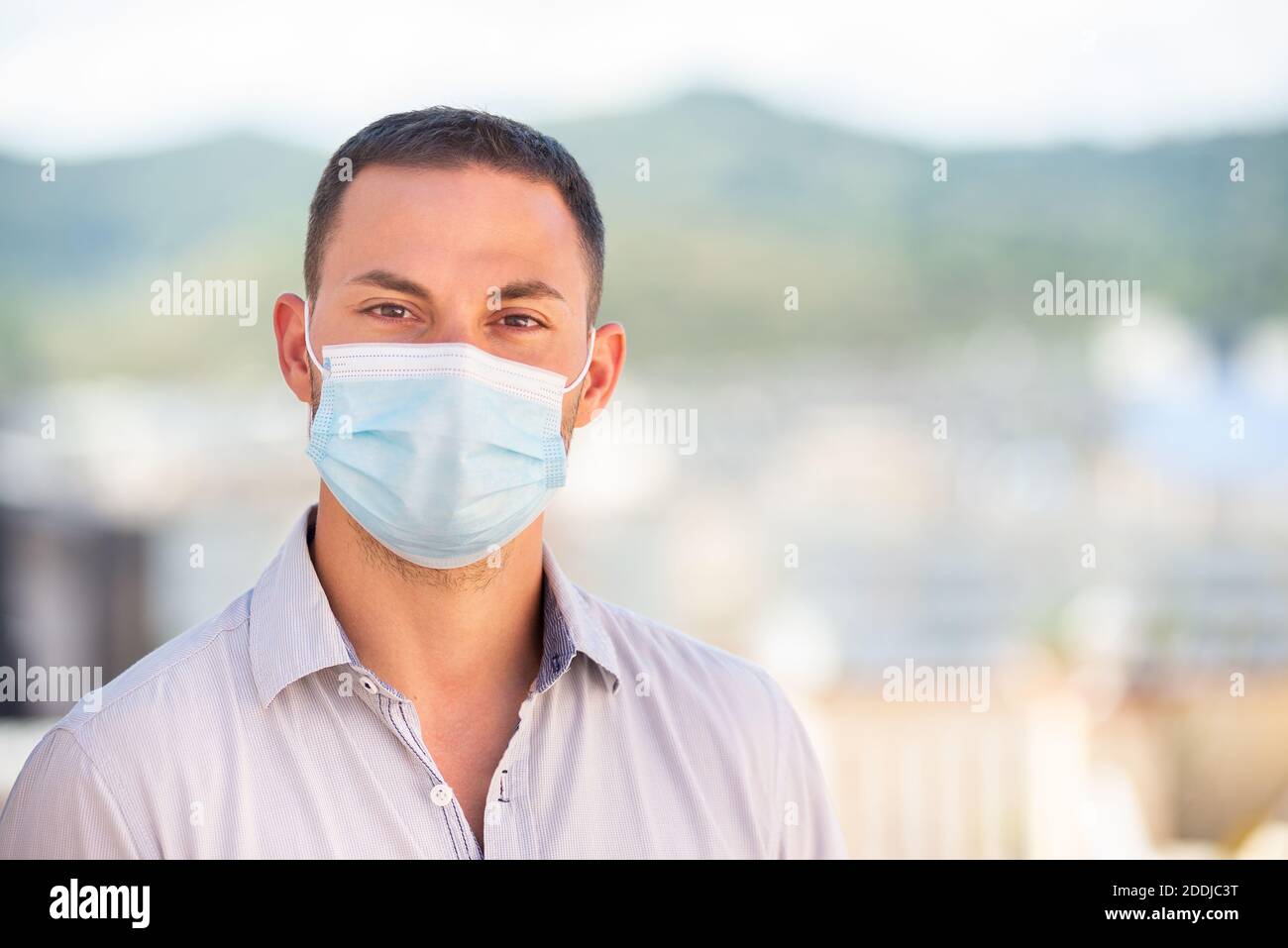 Giovane uomo che indossa una maschera di protezione del coronavirus Foto Stock