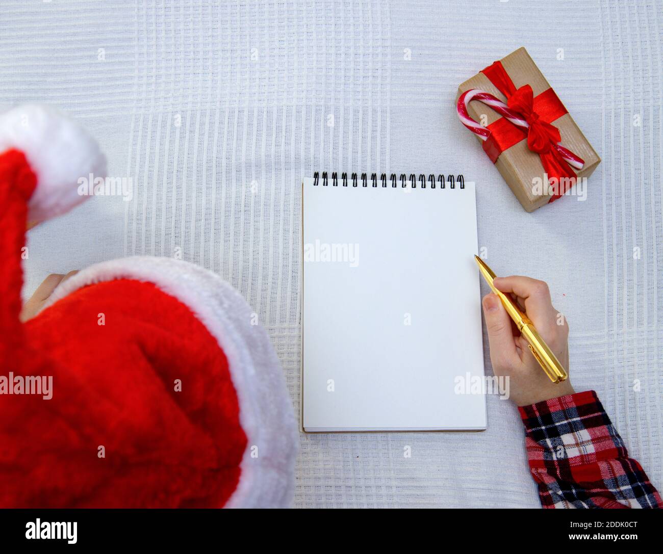 Il bambino scrive la lettera a Santa e ci è scatola con regali nelle vicinanze Foto Stock