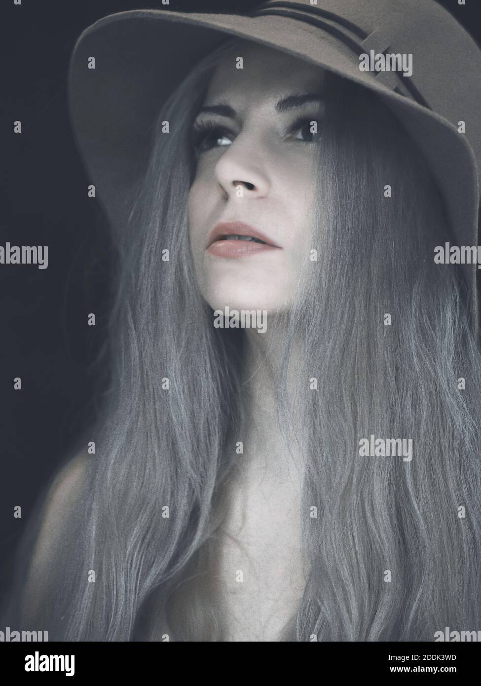 Bella donna con lunghi capelli grigio scuro che indossa un cappello Foto Stock
