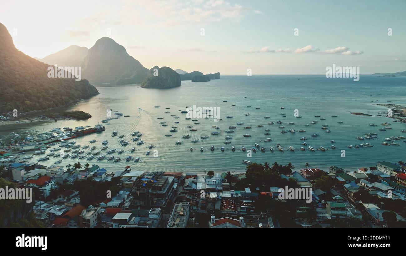 Porto di Ocean Bay con trasporto d'acqua in un paesaggio urbano tropicale. Maestoso paradiso resort con piccole imbarcazioni, edifici al sole sorgere al mattino d'estate. Mare sereno con navi, barche a Filippine isola Foto Stock