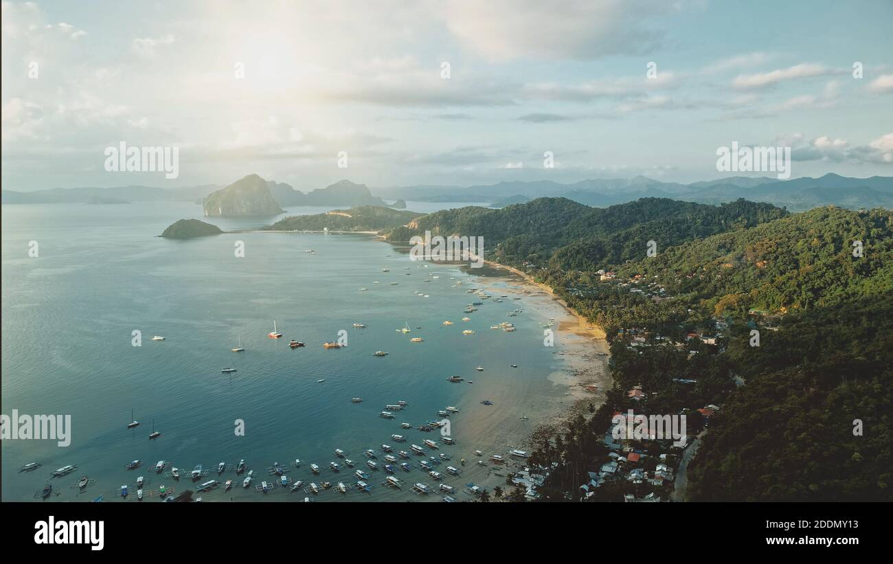 Ocean Pier città aerea: sun città paesaggio con molte barche, navi, navi al lungomare. Cottage e logge a palme verdi sulle colline. Trasporto d'acqua nella località tropicale filippina dell'isola di Palawan Foto Stock