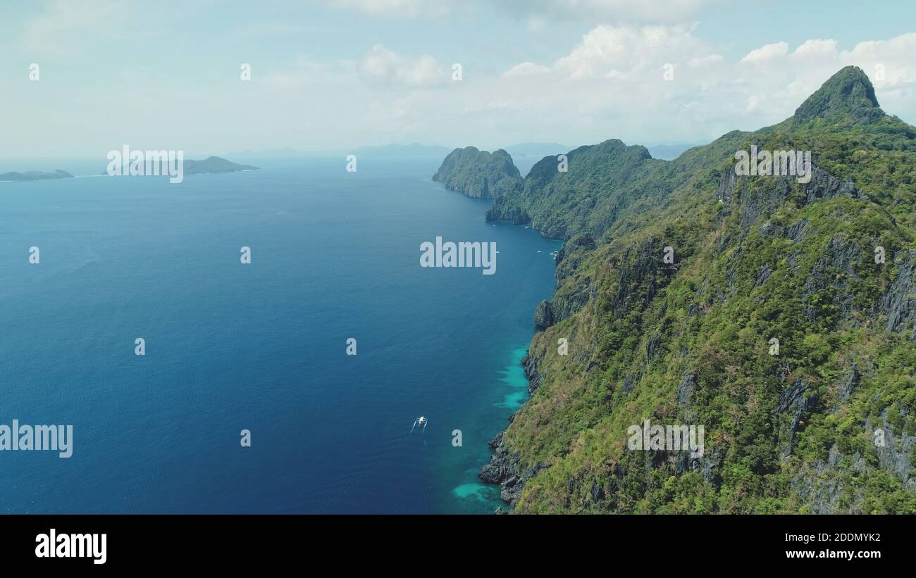 Vista aerea dell'isola di montagna con verde foresta tropicale. Paesaggio epico di oceano baia verde scogliera a spiaggia di sabbia. Barche al golfo di mare con mare turchese di Isola di Palawan, Filippine, Asia Foto Stock