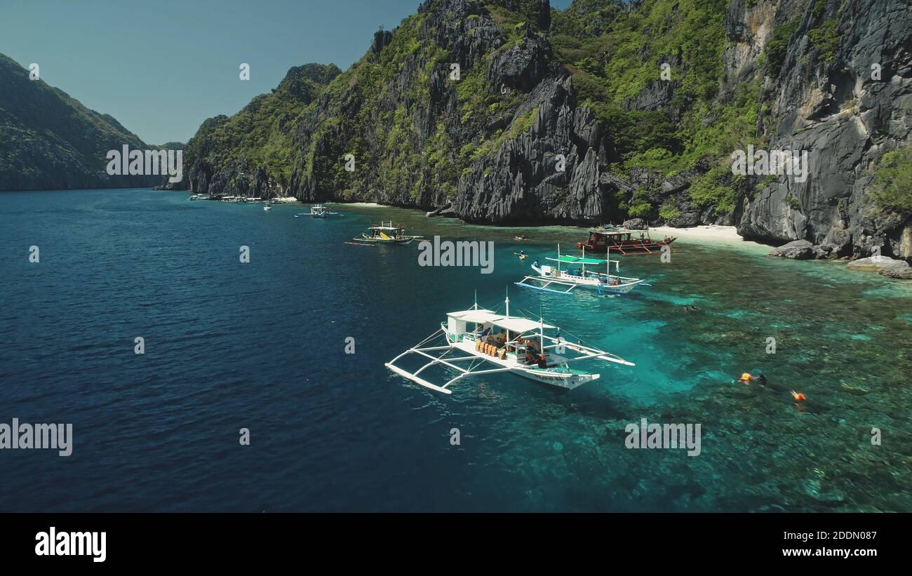 Mare blu con navi a mare baia. Passeggeri barche a bordo di una crociera estiva paradiso. Asia paesaggio naturale a isola collina di El Nido, Filippine, arcipelago di Visayas. Viaggio cinematografico nel golfo dell'oceano Foto Stock