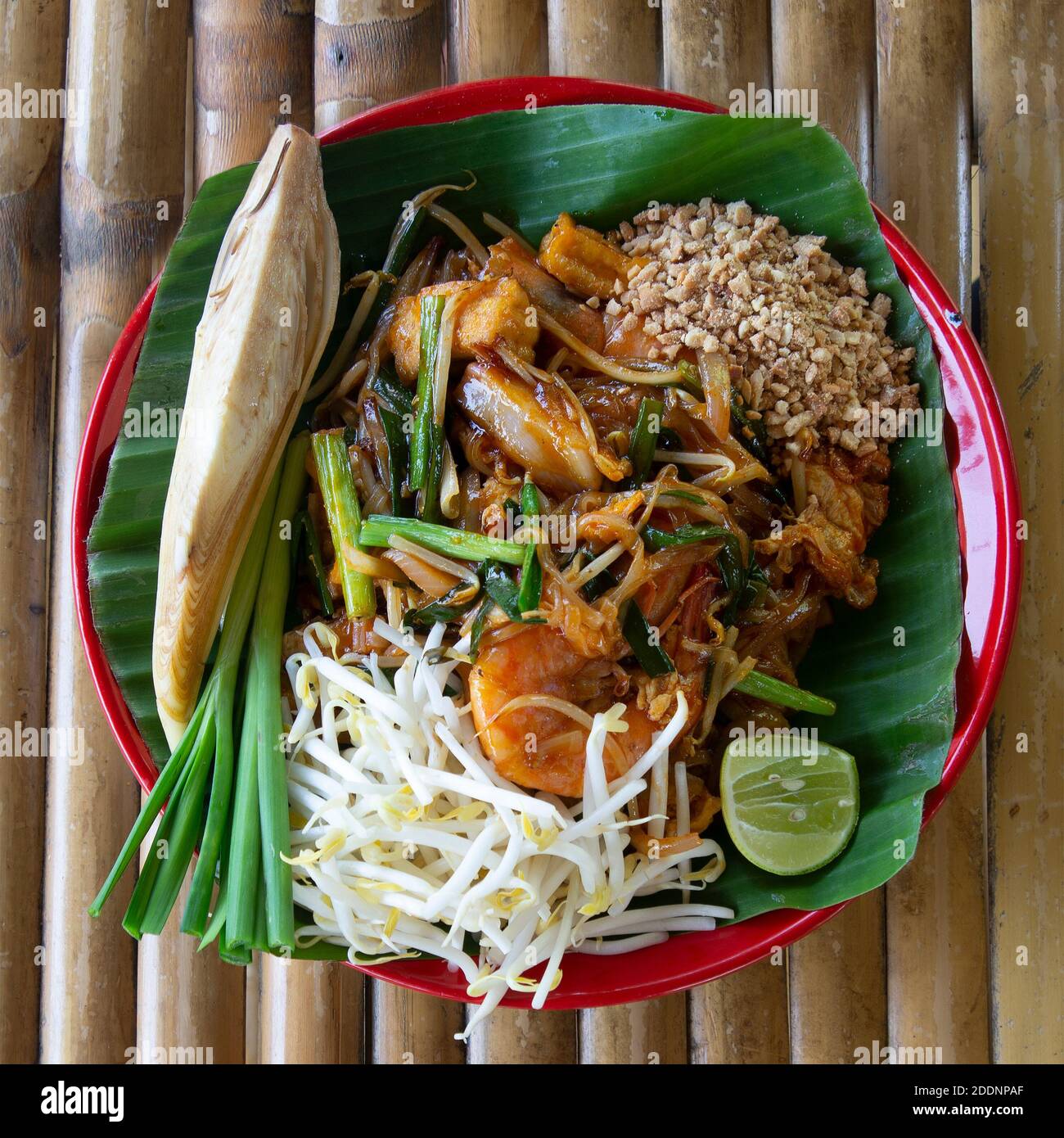 Vista dall'alto del cibo thailandese tradizionale, pad thai, servire su piatto su tavolo di bambù. Foto Stock