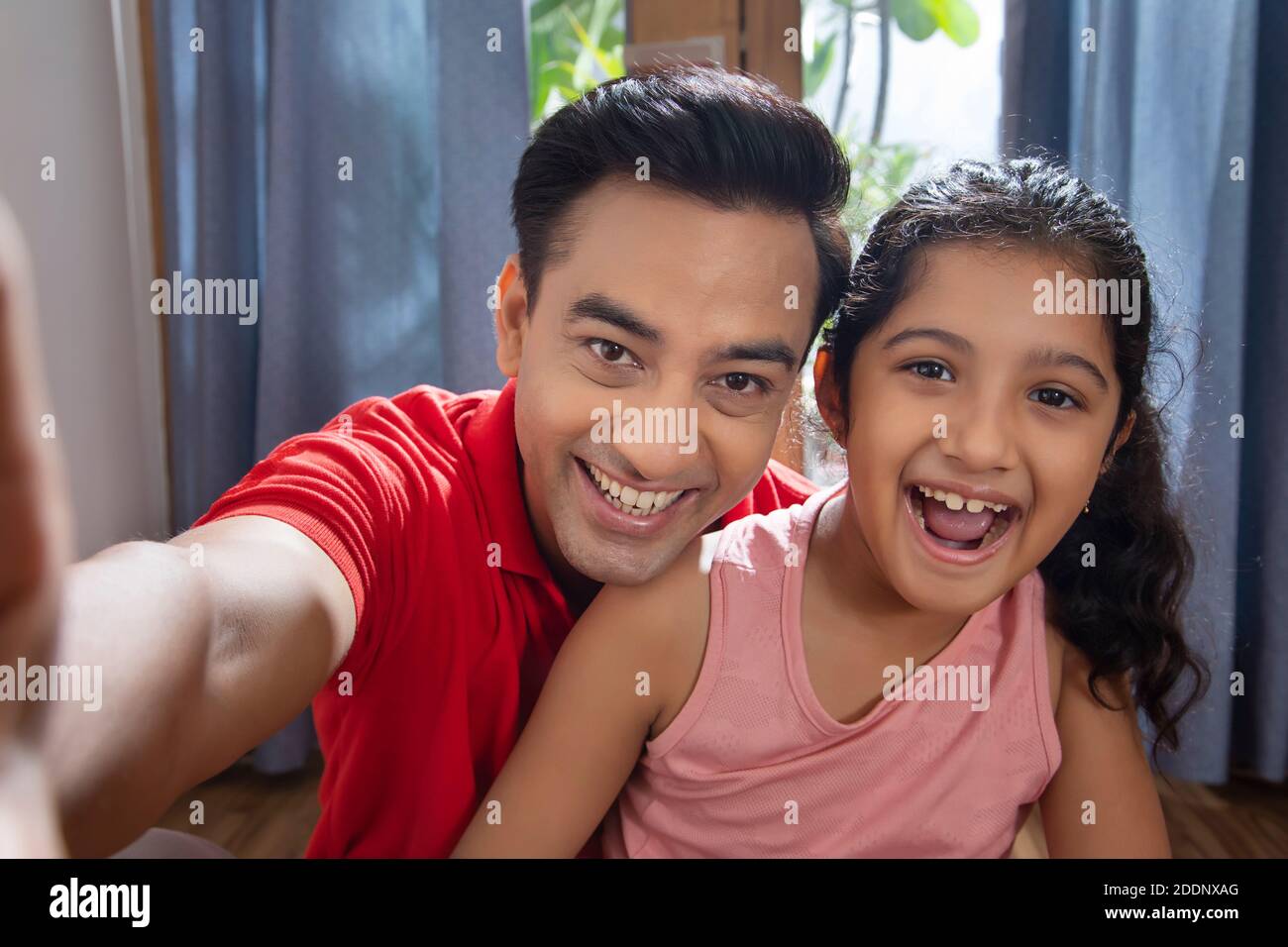 Padre e figlia si divertiscono a casa prendendo selfie con intelligenza telefono Foto Stock