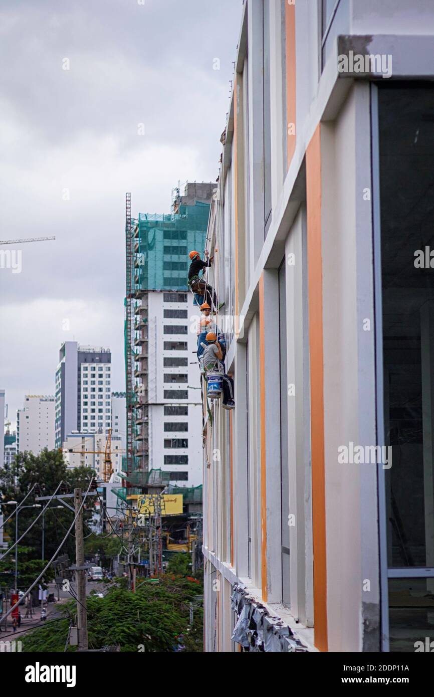 I pittori si aggrappano alle loro corde mentre lavorano su un muro. Foto Stock