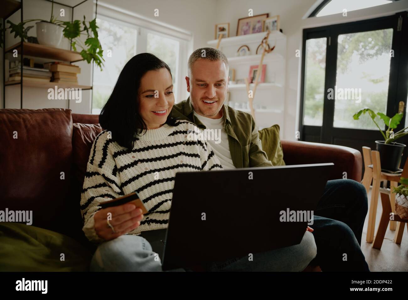 Donna felice con il marito che inserisce i dettagli della carta di credito per online acquisto con il marito a casa Foto Stock