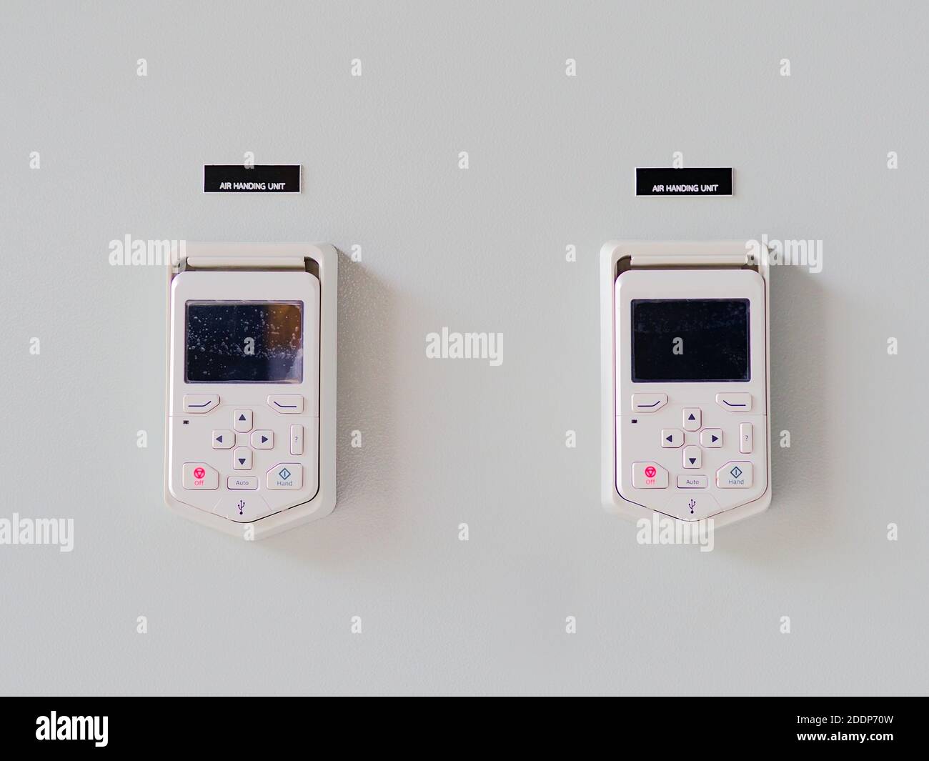 Un primo piano dei telecomandi rimovibili dell'unità di trattamento aria fissato a una parete bianca Foto Stock