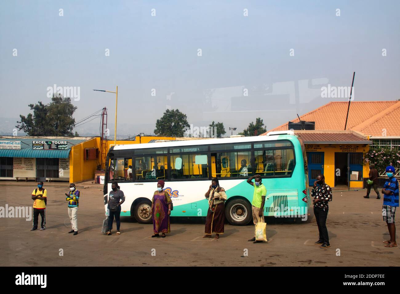 Passeggeri in attesa che l'autista apra la porta dell'autobus alla stazione degli autobus di Giporoso. Prima che i passeggeri entrino in autobus, si suppone che si lavino le mani e indossino maschere facciali. Remera, Kigali, Ruanda. Foto Stock