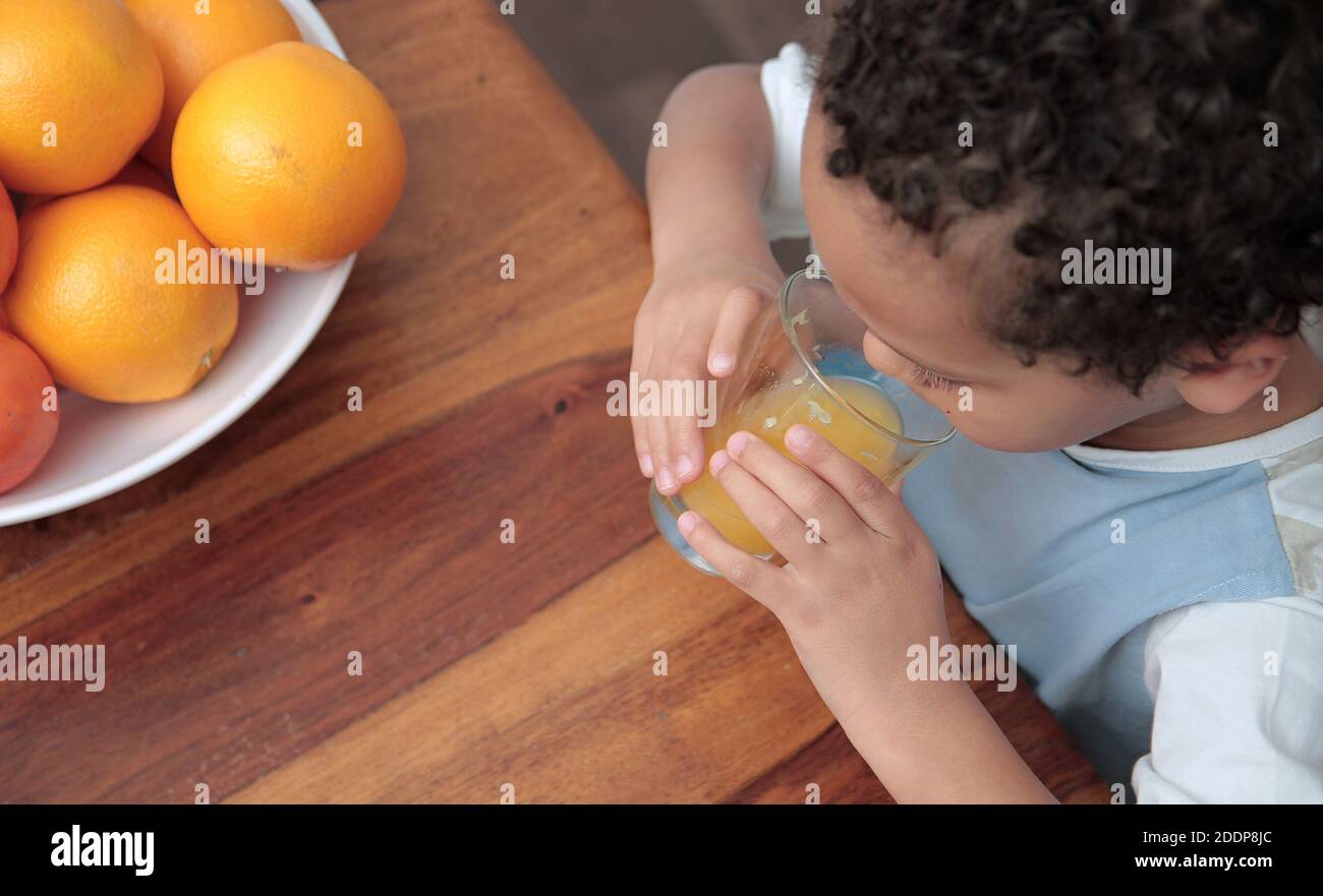 bambino che beve un bicchiere di succo di frutta arancione che promuove sano mangiare stock foto Foto Stock