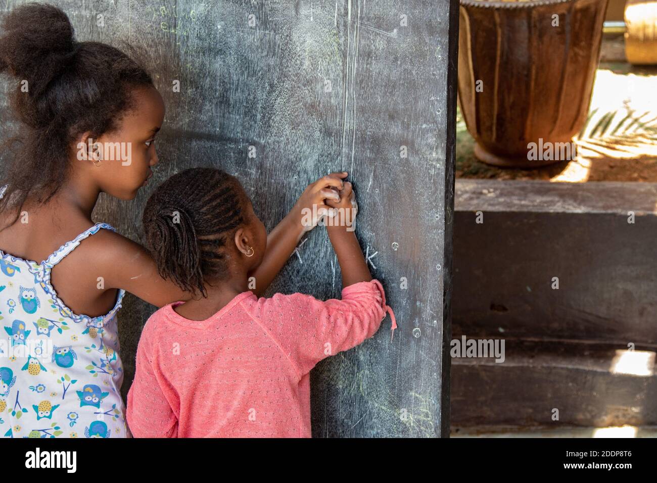 Amilia, di 6 anni, revisionando con la sorella Kalena a casa. A causa dell'epidemia di coronavirus, le scuole materne sono ancora chiuse in Ruanda e alcune famiglie assumono insegnanti per aiutare i loro bambini a casa. Cella di Karugira, Kigali, Ruanda. Foto Stock