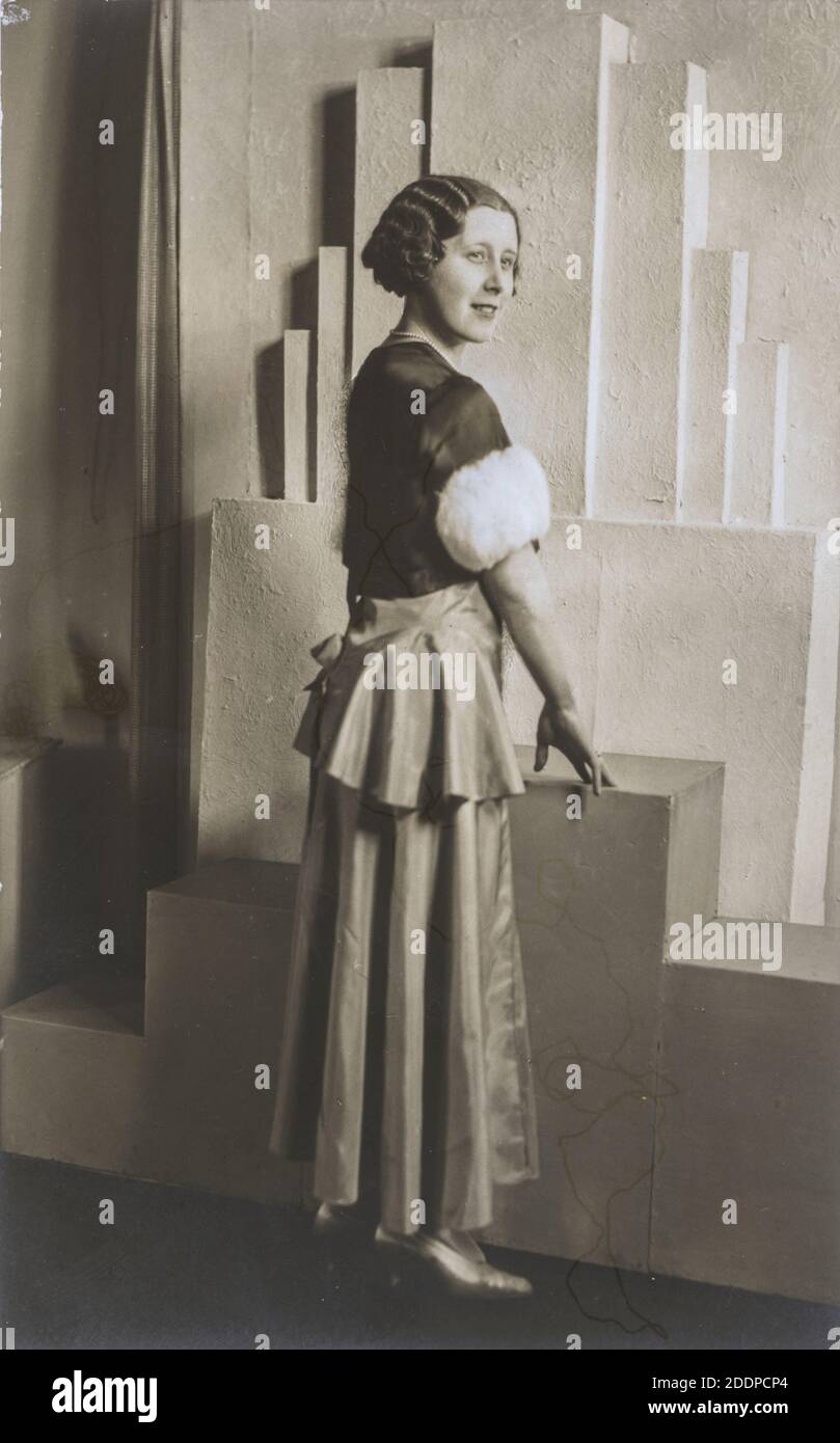 Ritratto in studio bianco e nero di donna in piedi in abito da sera con sfondo Art Deco. Circa 1930, Inghilterra. Foto Stock