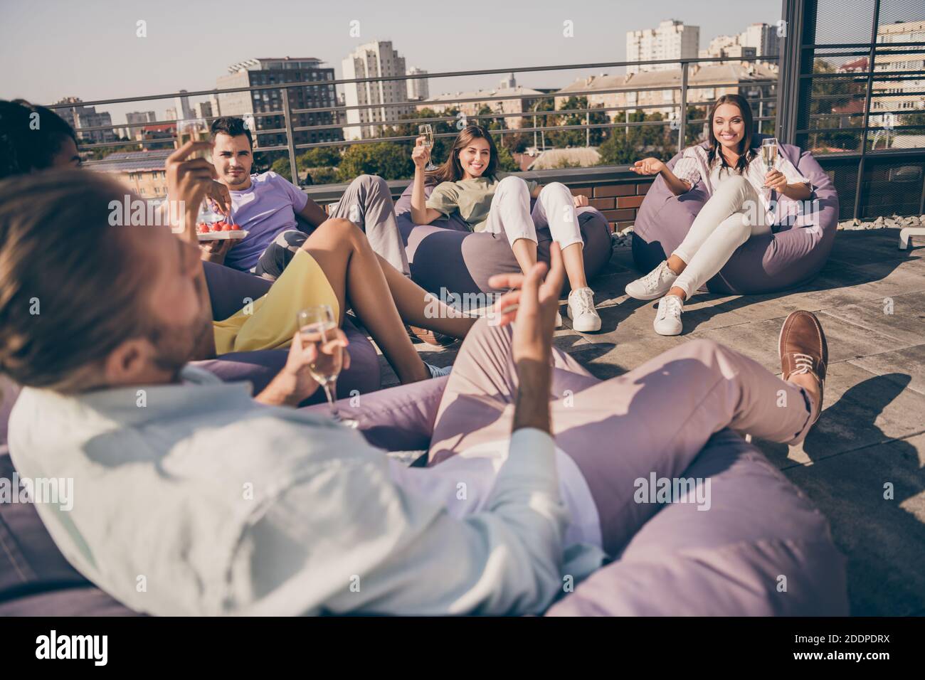 Foto di un gruppo di persone allegre e allegre, giovani sorridenti siediti nella poltrona in sacco beans e bevi il vino all'esterno sul tetto Foto Stock