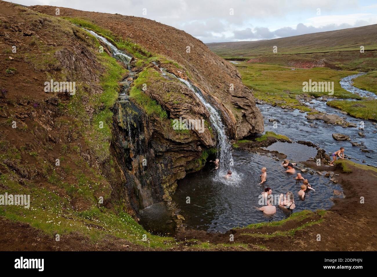 Persone che fanno il bagno nella piscina naturale sotto una calda cascata sul Monte Laugarfell, Islanda, Laugarvallardalur Foto Stock