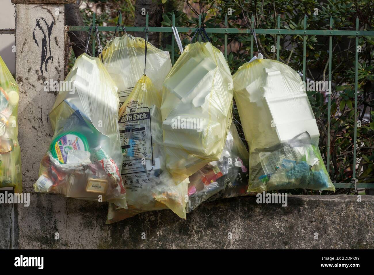 Sacchetti gialli per rifiuti di plastica, appesi su una recinzione da giardino, Germania Foto Stock