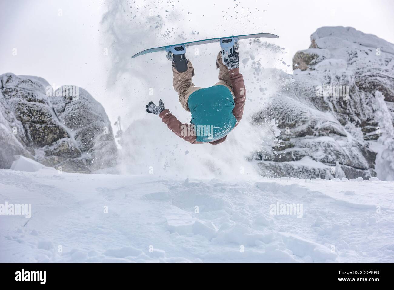 Lo snowboarder fa un pericoloso trucco con il salto e il ribaltamento in polvere neve Foto Stock