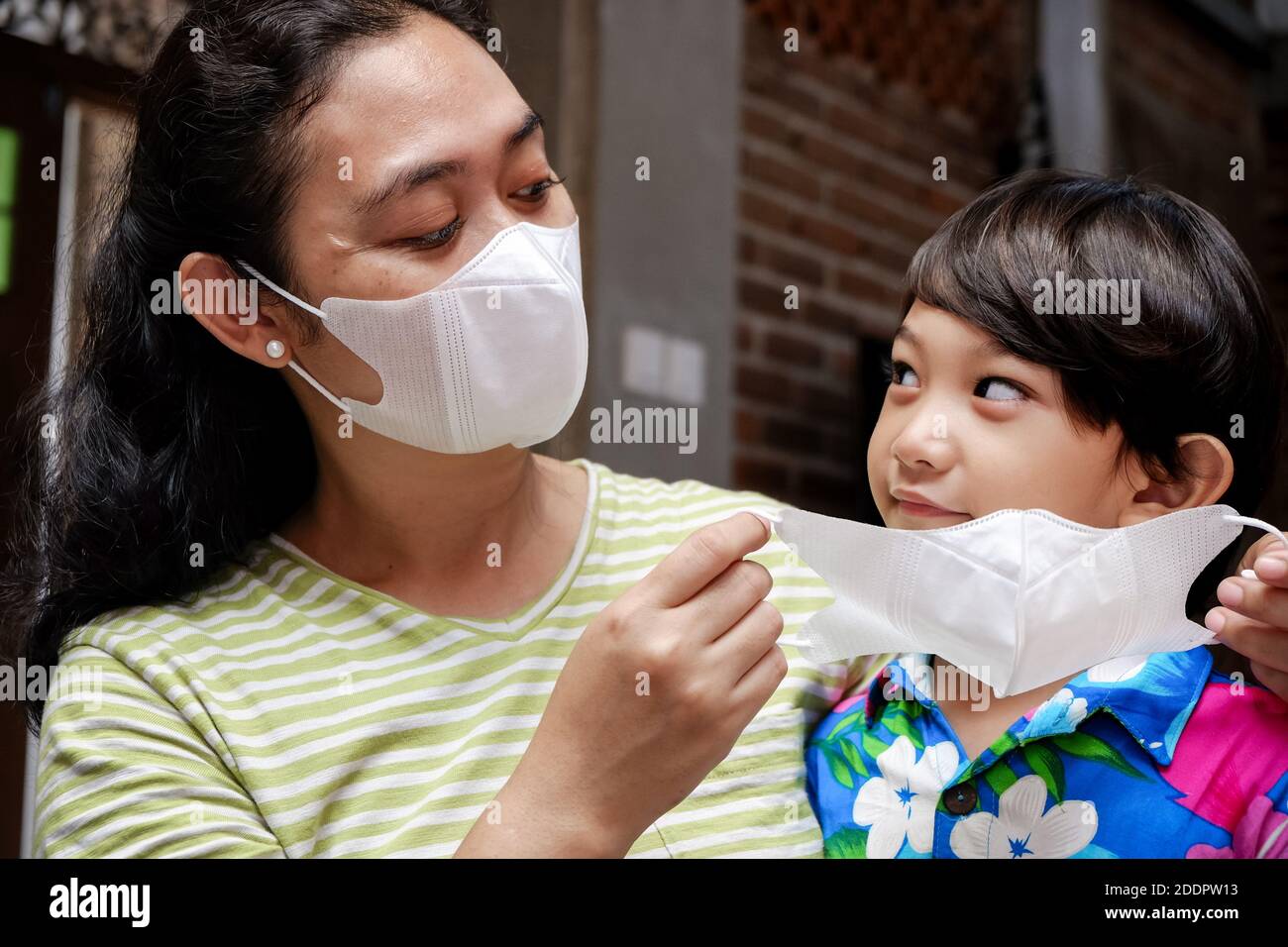 Madre del sud-est asiatico che aiuta il bambino usando la maschera di faccia Foto Stock