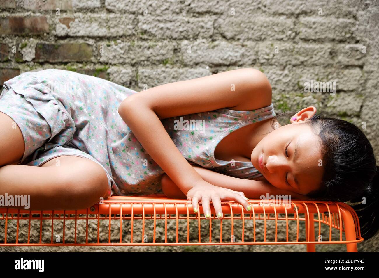 Etnia del sud-est asiatico adolescente ragazza sdraiata su una panchina, prendere il sole la mattina a casa Foto Stock