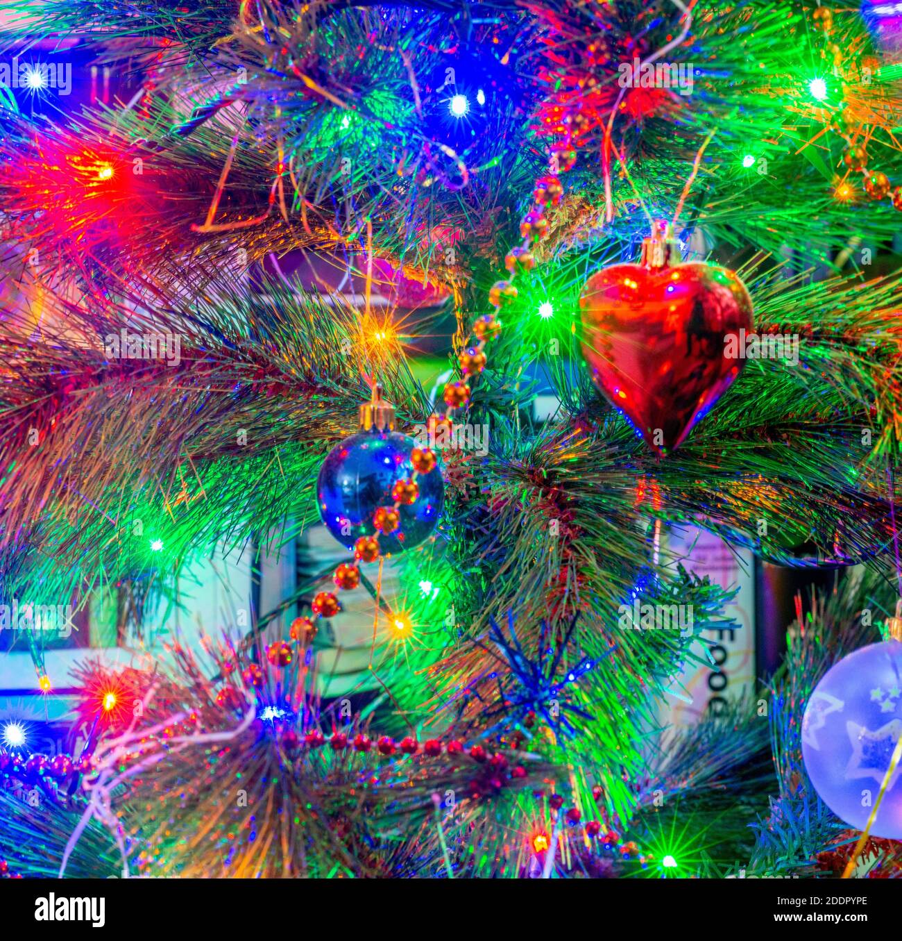 Primo piano di colorate luci di Natale che decorano un albero, baubles appeso Foto Stock