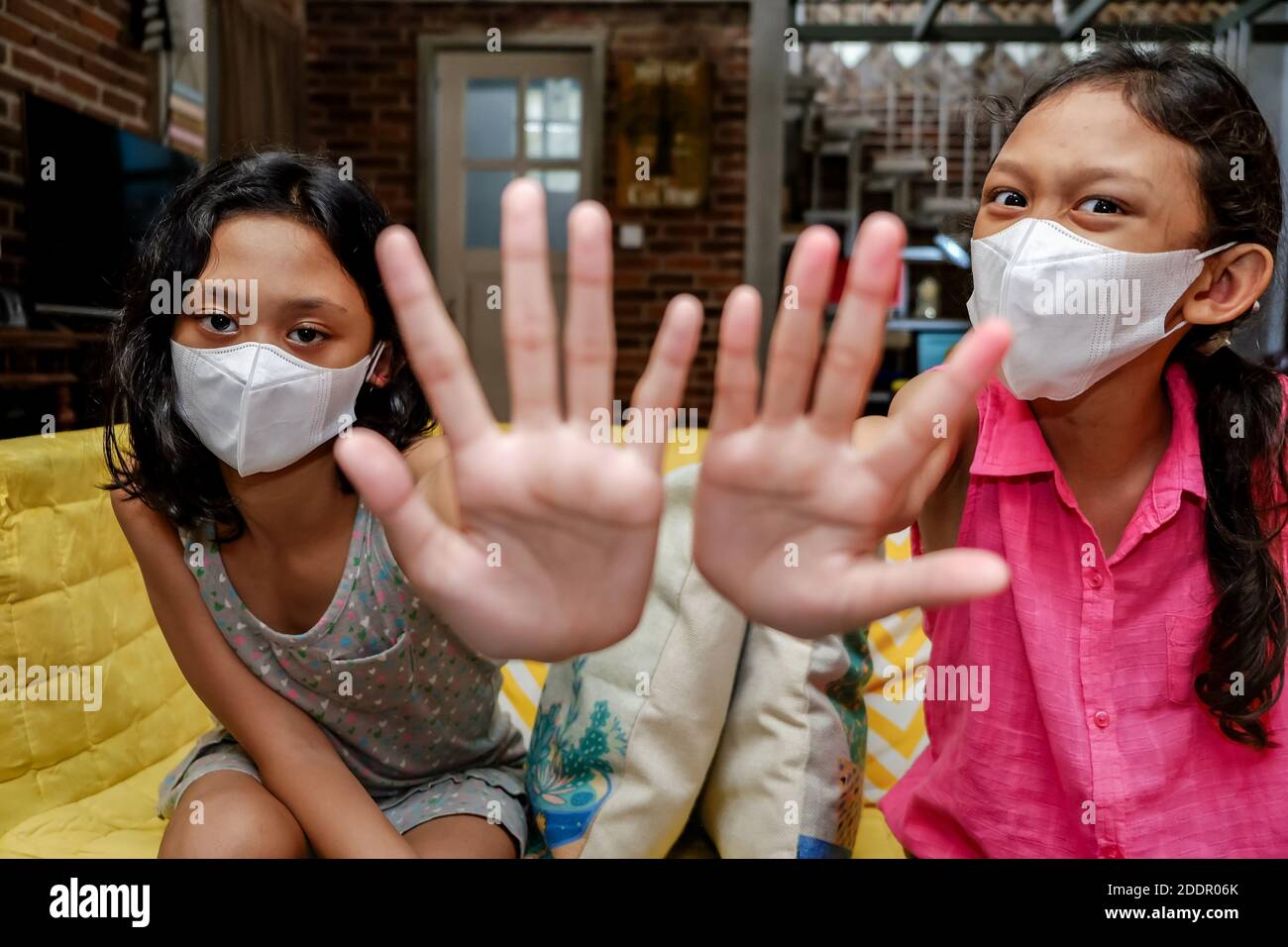 Sudest Asiatico Teenage Girls indossare maschera medica faccia fare arresto Segni gesti con le mani Foto Stock