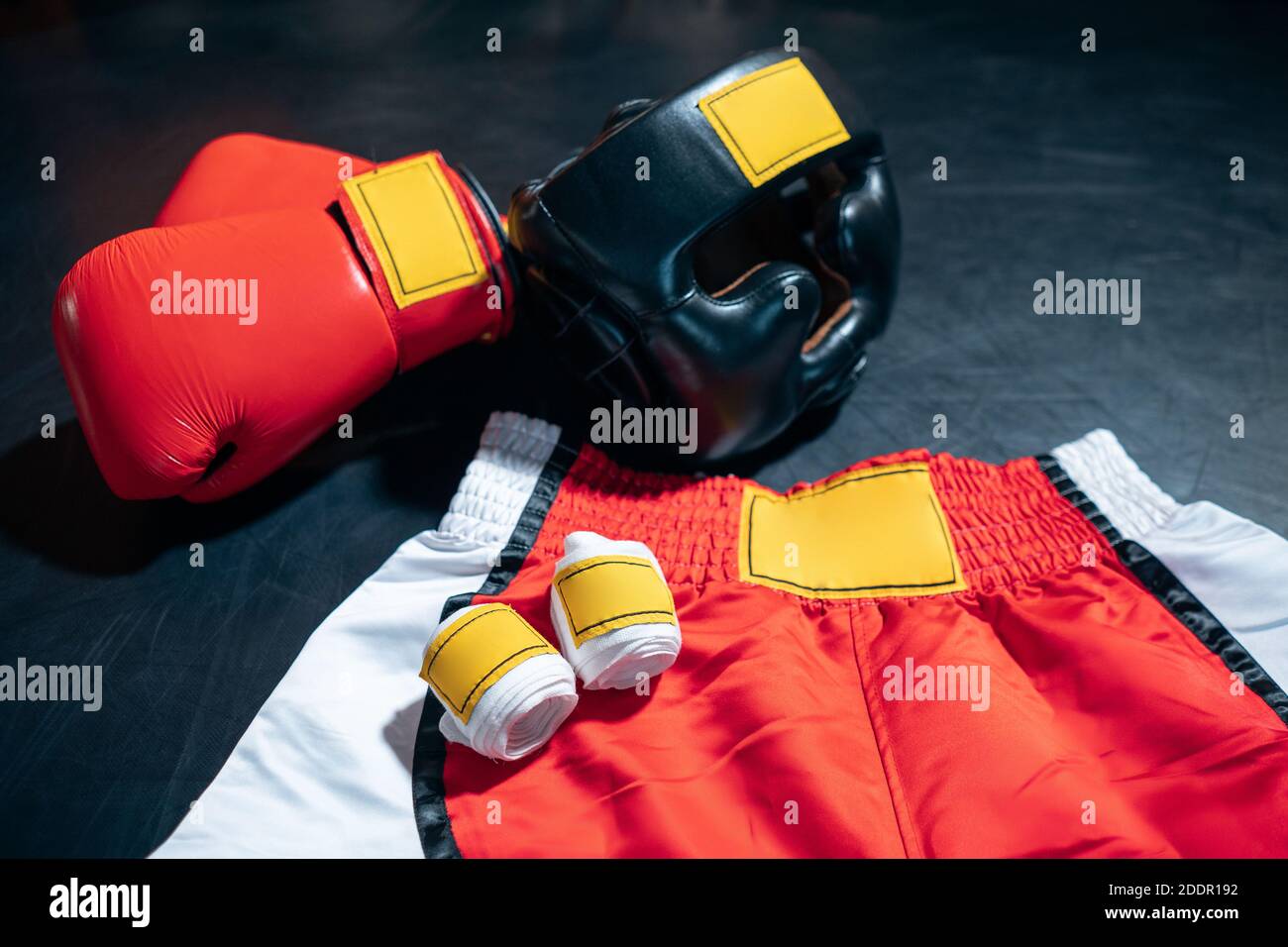 vista dall'alto di guanti da boxe, pantaloncini, casco e nastro adesivo su sfondo nero Foto Stock