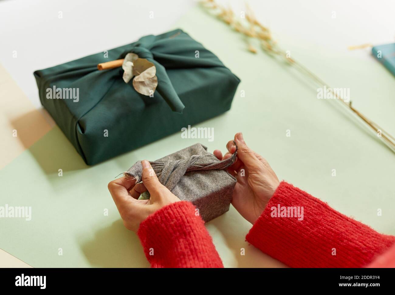 Le mani della donna preparano il presente, avvolgendolo in un panno grigio. Concetto di Natale e Capodanno, 4k Foto Stock