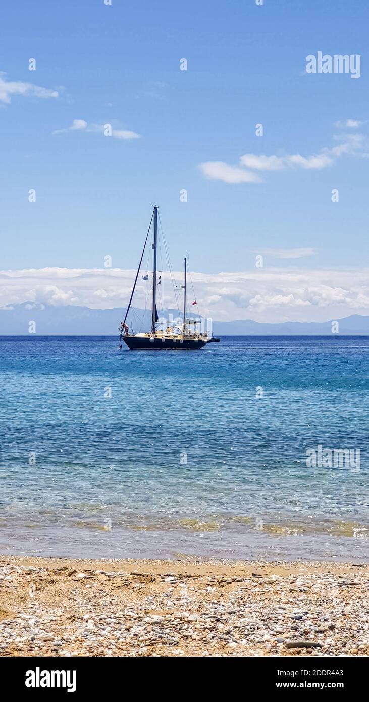 Piccolo yacht turistico che naviga vicino alla spiaggia sulle onde blu da destra a sinistra. Foto Stock