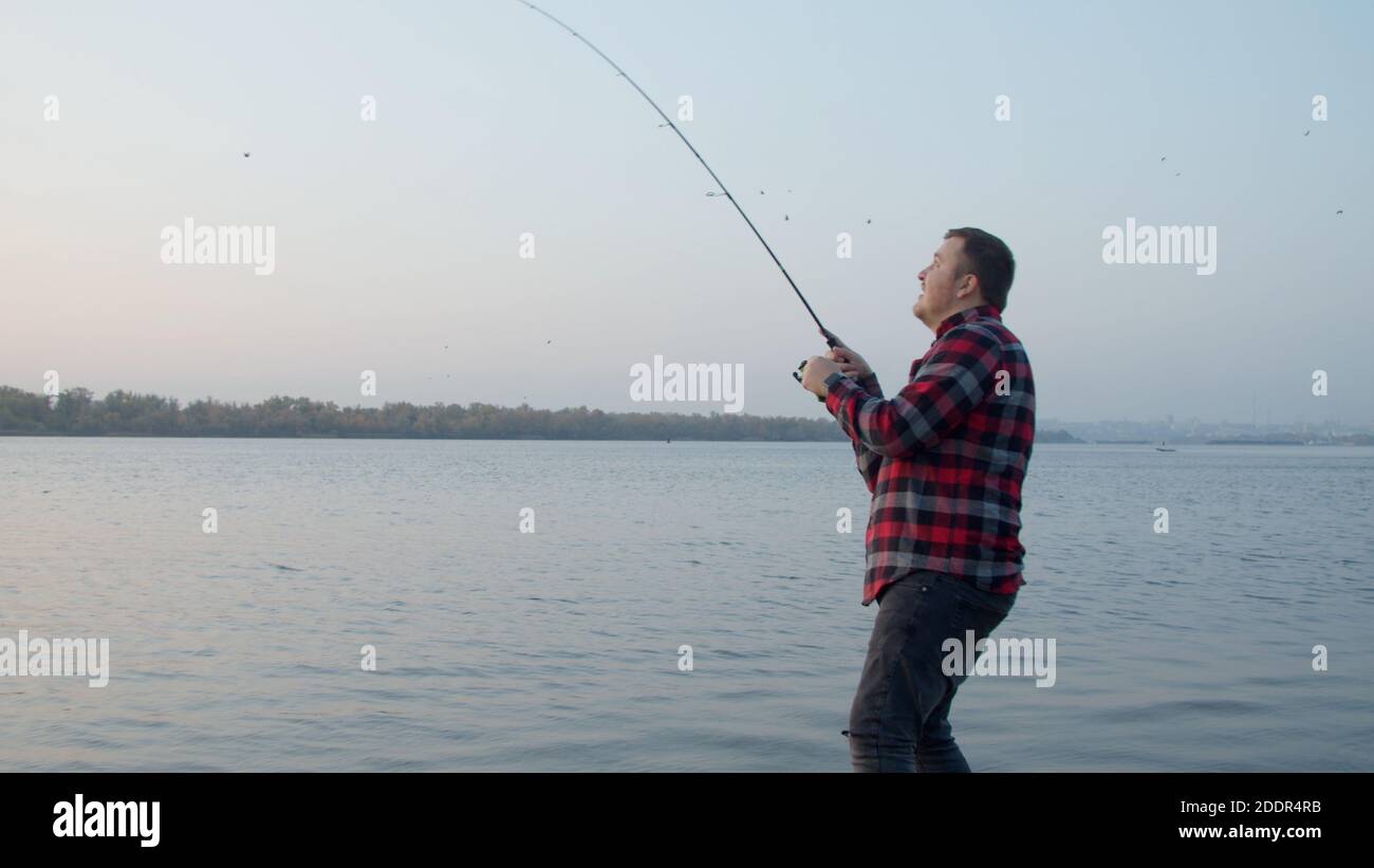 Pescatore maschio che prende selfie con pesci vicino all'acqua Foto Stock