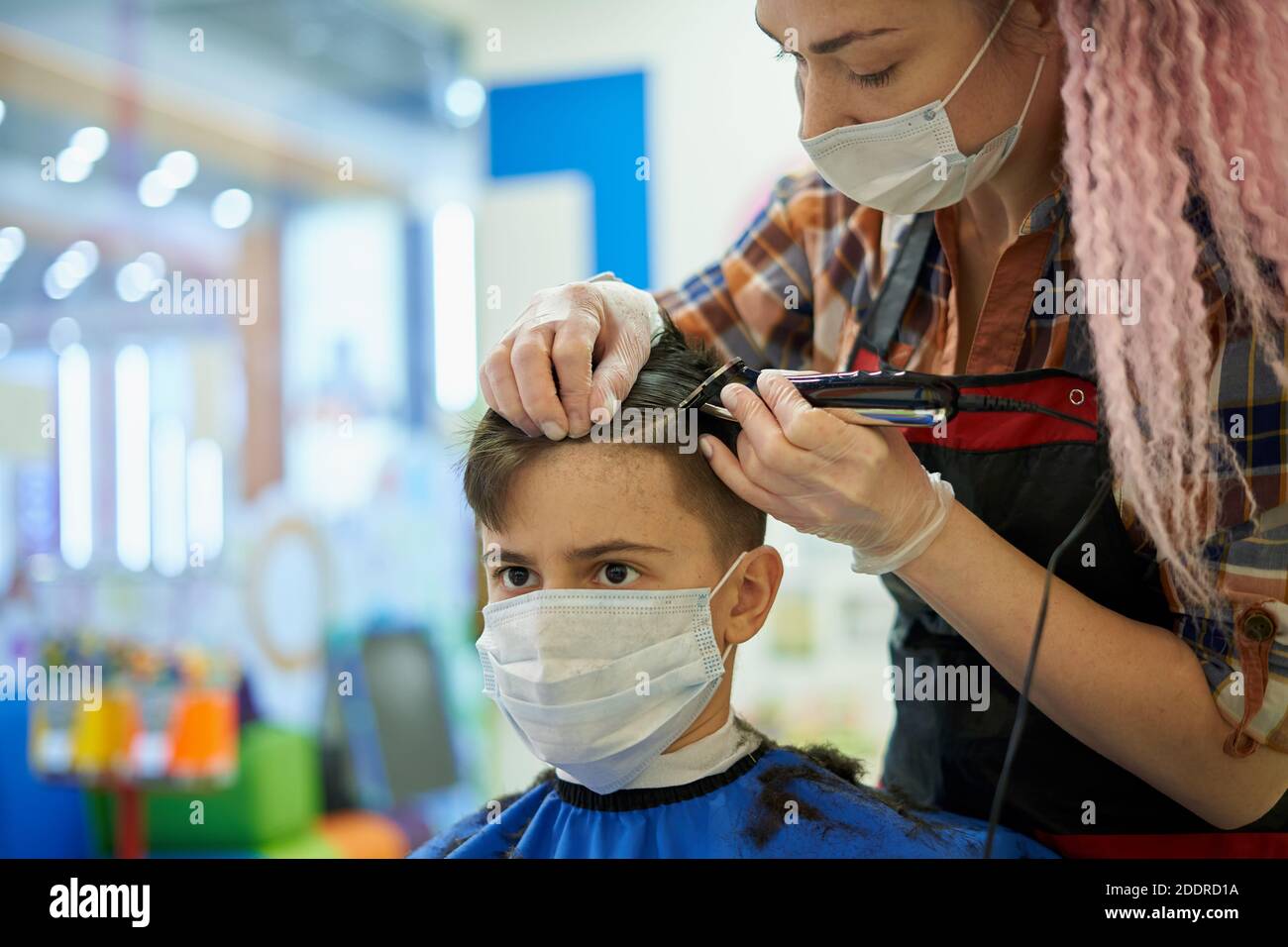 Ragazzo adolescente che indossa la maschera al barbiere durante la pandemia Foto Stock